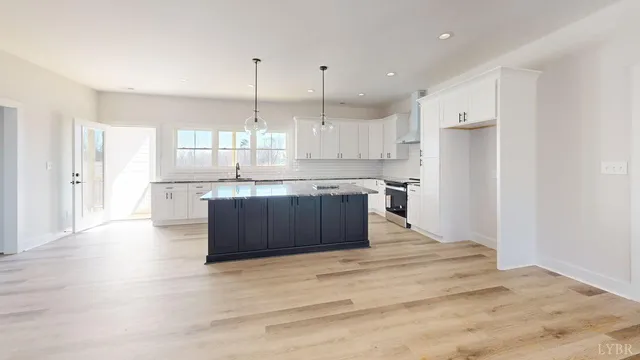 a kitchen with stainless steel appliances granite countertop a refrigerator a sink dishwasher a stove and white cabinets with wooden floor