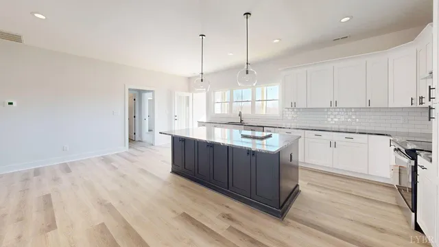 a kitchen with stainless steel appliances granite countertop a sink a stove a refrigerator and white cabinets with wooden floor