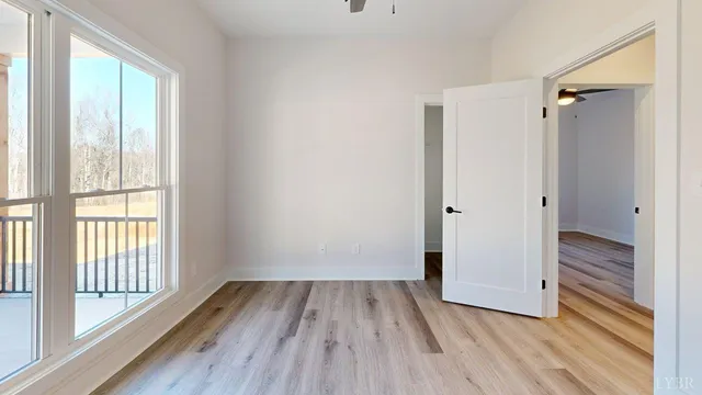 a view of empty room with wooden floor and fan