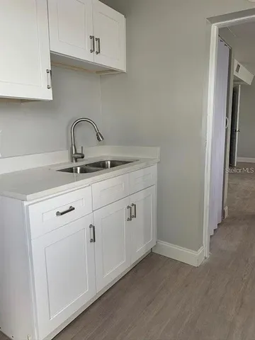 a kitchen with white cabinets and sink