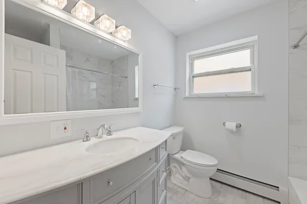 a bathroom with a granite countertop sink a toilet and a mirror
