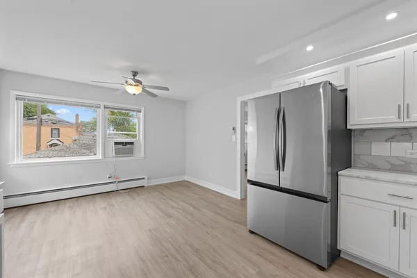 a view of kitchen with stainless steel appliances granite countertop a refrigerator a sink and white cabinets with wooden floor