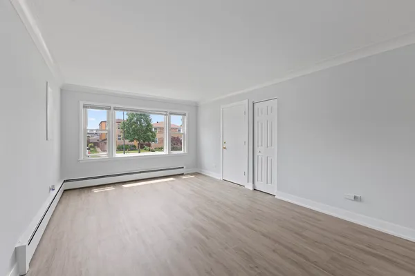 a view of an empty room with wooden floor and a window