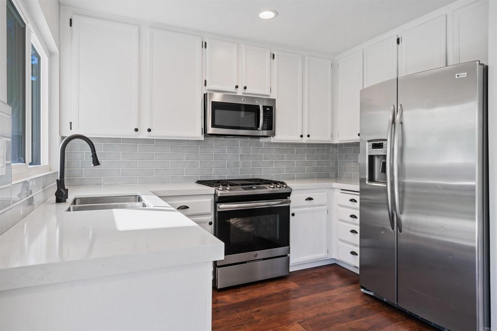 4435 Springtime Drive Oceanside, CA 92056 - Photo 5 of 22 a kitchen with a refrigerator stove and white cabinets