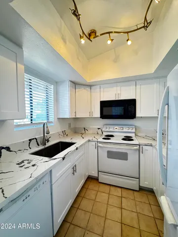 a kitchen with a sink window and white cabinets