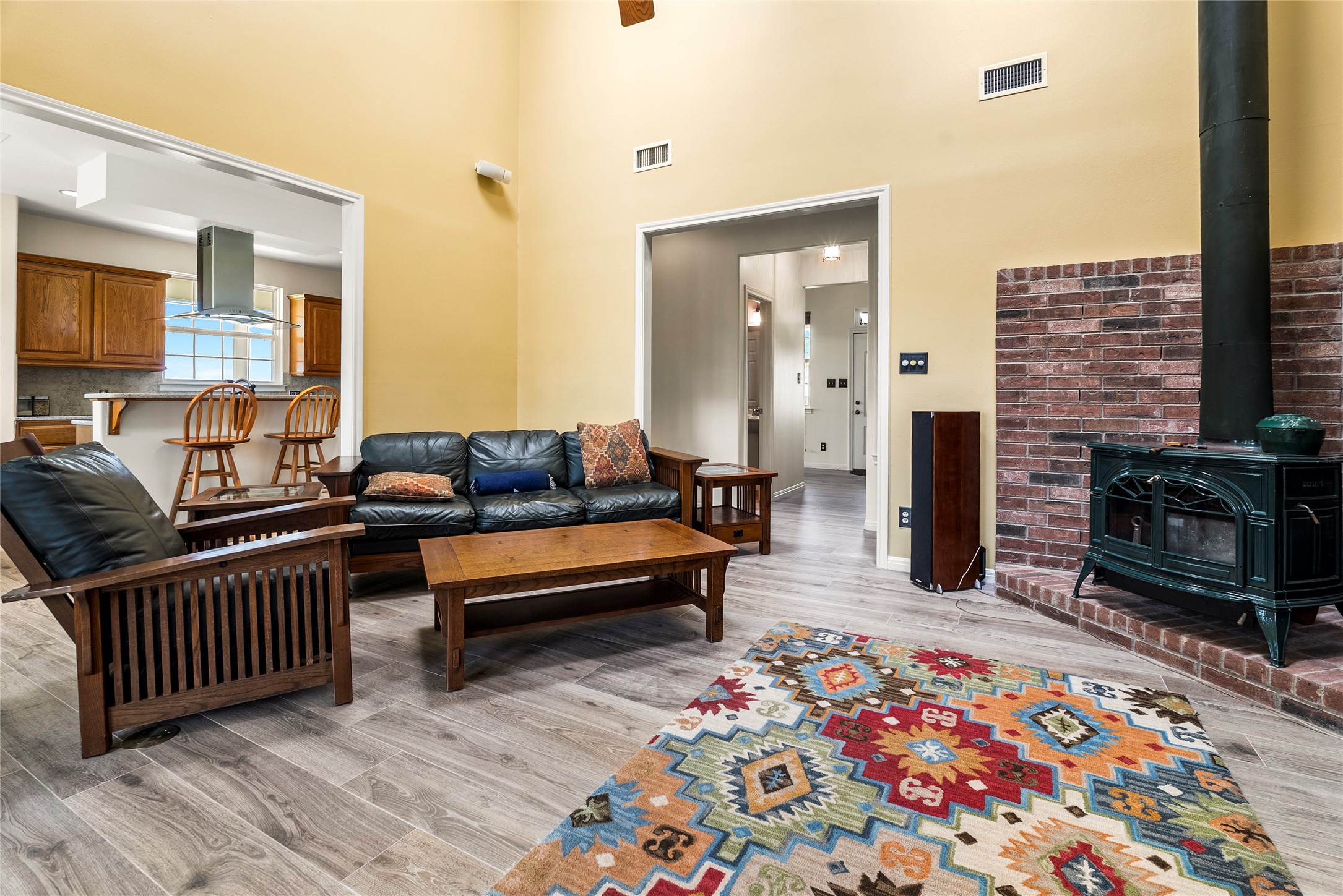928 Upper Elgin River Road Elgin, TX 78621 - Photo 10 of 40 Open-concept living area featuring high vaulted ceilings, light wood-finish flooring, and a brick-faced wood-burning fireplace.