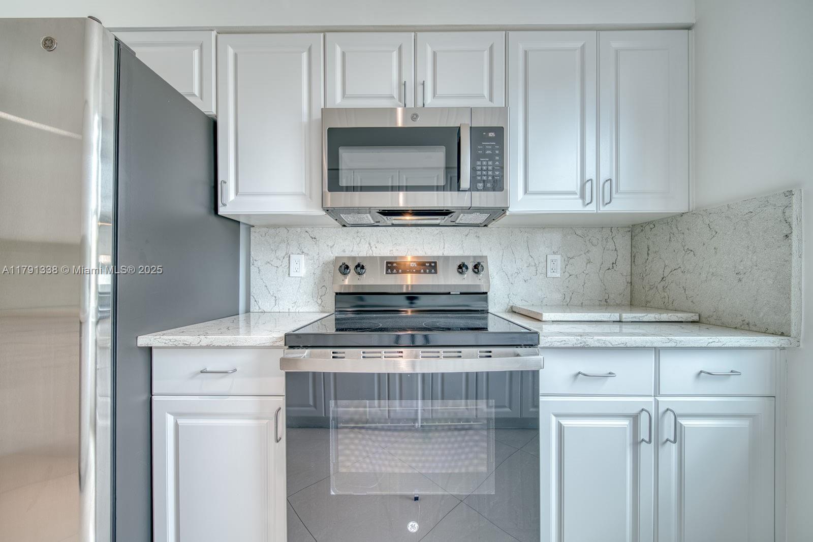 90 Alton Road, Unit TH2 Miami Beach, FL 33139 - Photo 8 of 32 a kitchen with stainless steel appliances granite countertop a stove a microwave and cabinets