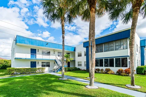 a front view of a building with a garden and trees