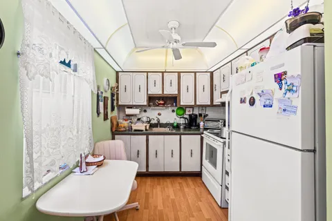 a kitchen with granite countertop a white refrigerator a sink dishwasher a dining table and chairs with wooden floor