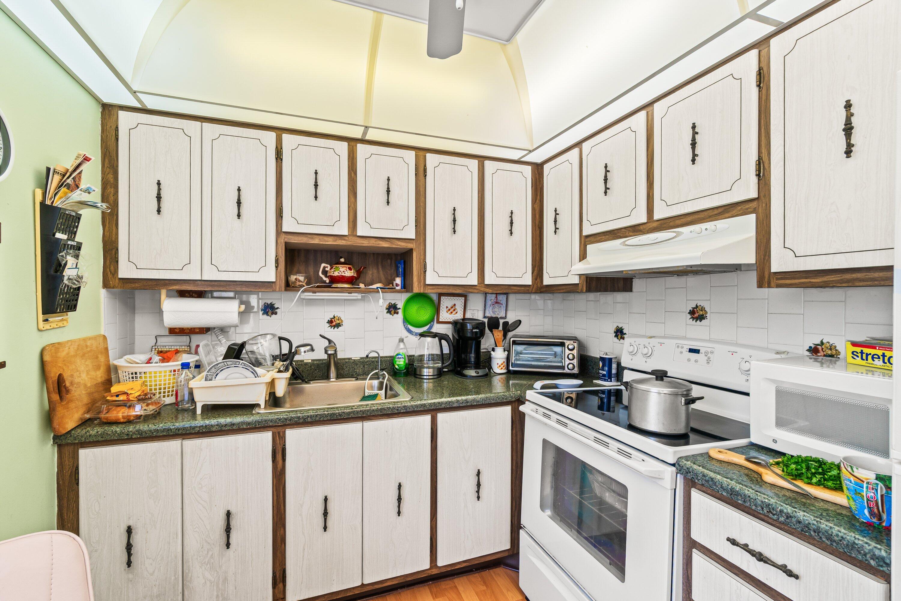 508 Normandy Lane, Unit 508 Delray Beach, FL 33484 - Photo 8 of 25 a kitchen with stainless steel appliances granite countertop white cabinets a stove a sink and dishwasher