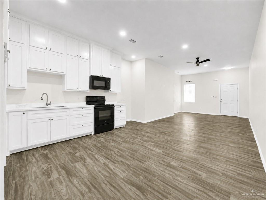 618 West 25th Street Mission, TX 78574 - Photo 4 of 8 Open-concept interior featuring wood-finish flooring, recessed lighting, a modern ceiling fan, and a kitchen with white cabinetry and black appliances