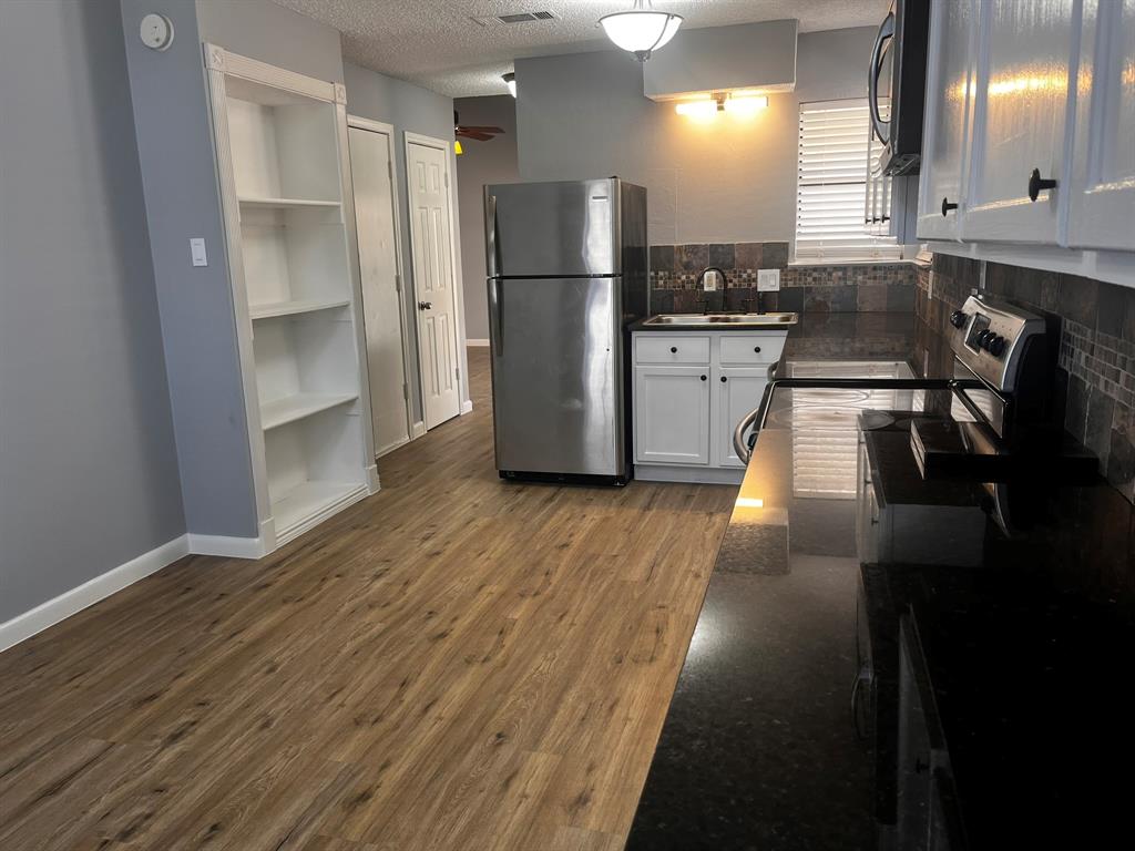 1007 Mack Place Denton, TX 76209 - Photo 9 of 37 Kitchen with stainless steel appliances, white cabinetry, dark wood-type flooring, a textured ceiling, and decorative backsplash