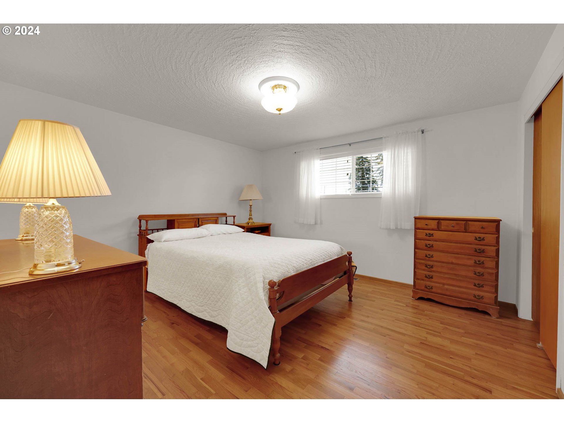 2411 15th Street Springfield, OR 97477 - Photo 8 of 18 a bedroom with a bed and a night stand with wooden floor