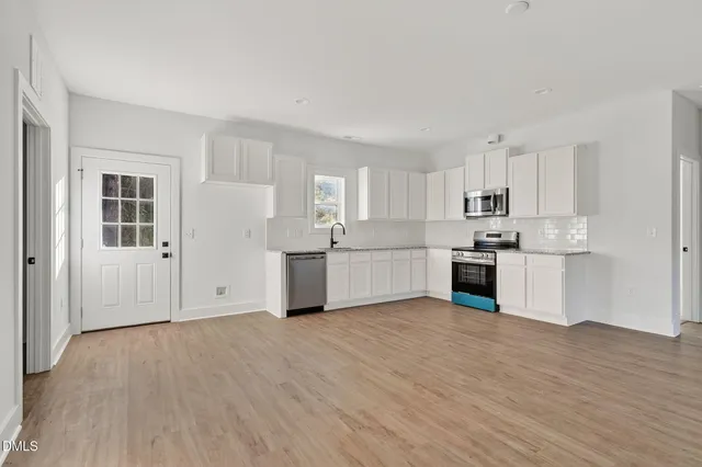a view of a kitchen with a sink and dishwasher with wooden floor