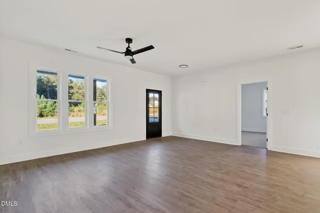 a view of an empty room with a window and wooden floor