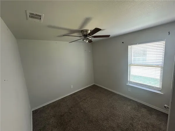 an empty room with a window and a fan