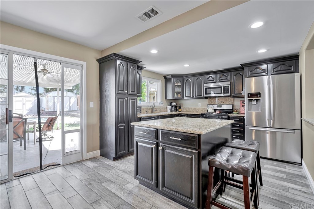 23682 Cavanaugh Road Lake Forest, CA 92630 - Photo 21 of 51 a kitchen with kitchen island a stove a refrigerator and wooden cabinets