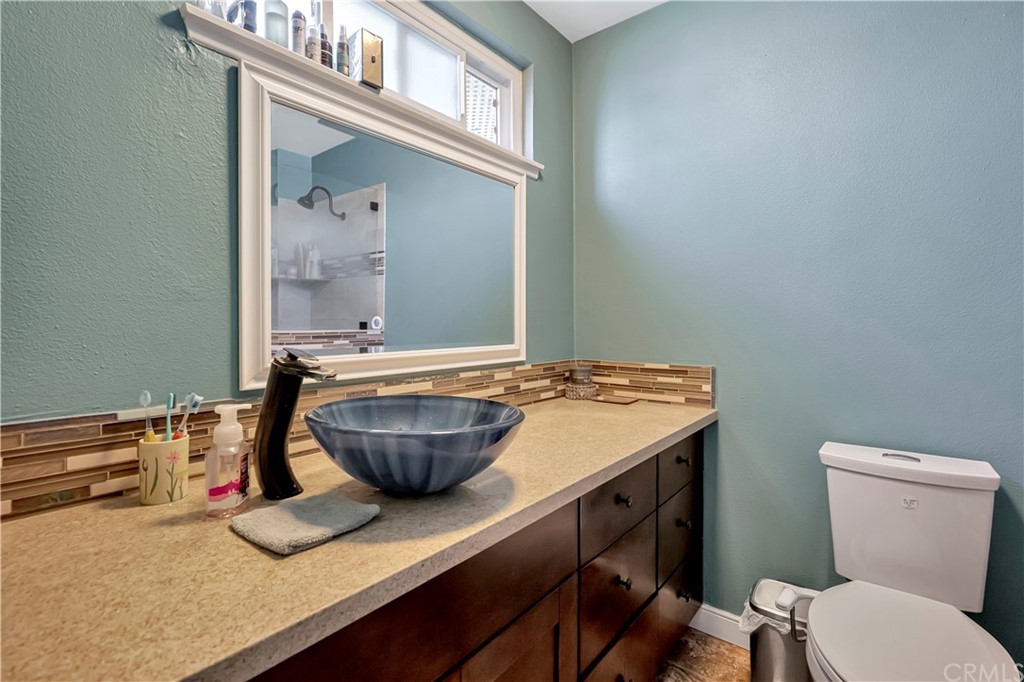 23682 Cavanaugh Road Lake Forest, CA 92630 - Photo 30 of 51 a bathroom with a granite countertop sink a toilet and a mirror