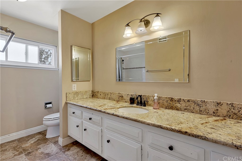 23682 Cavanaugh Road Lake Forest, CA 92630 - Photo 37 of 51 a bathroom with a granite countertop toilet a sink and a mirror