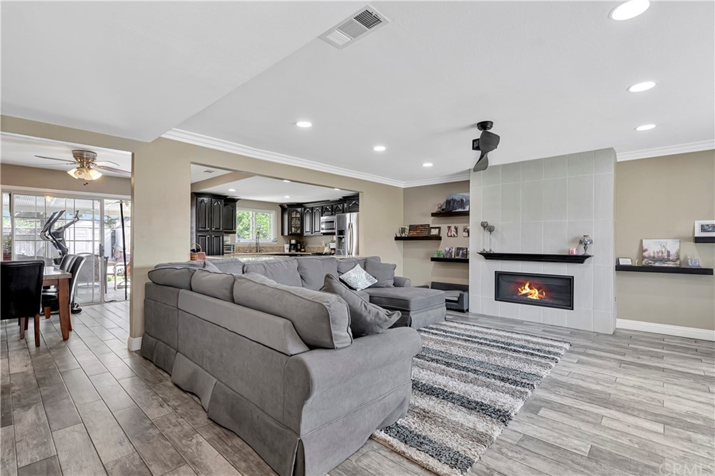 23682 Cavanaugh Road Lake Forest, CA 92630 - Photo 9 of 51 a living room with furniture a fireplace and a dining table with wooden floor