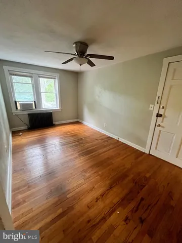 a view of a livingroom with wooden floor a ceiling fan and windows