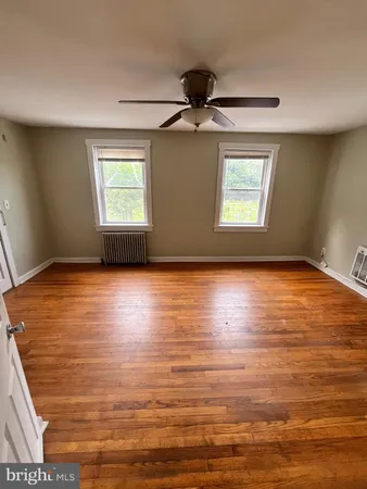 an empty room with wooden floor fan and windows