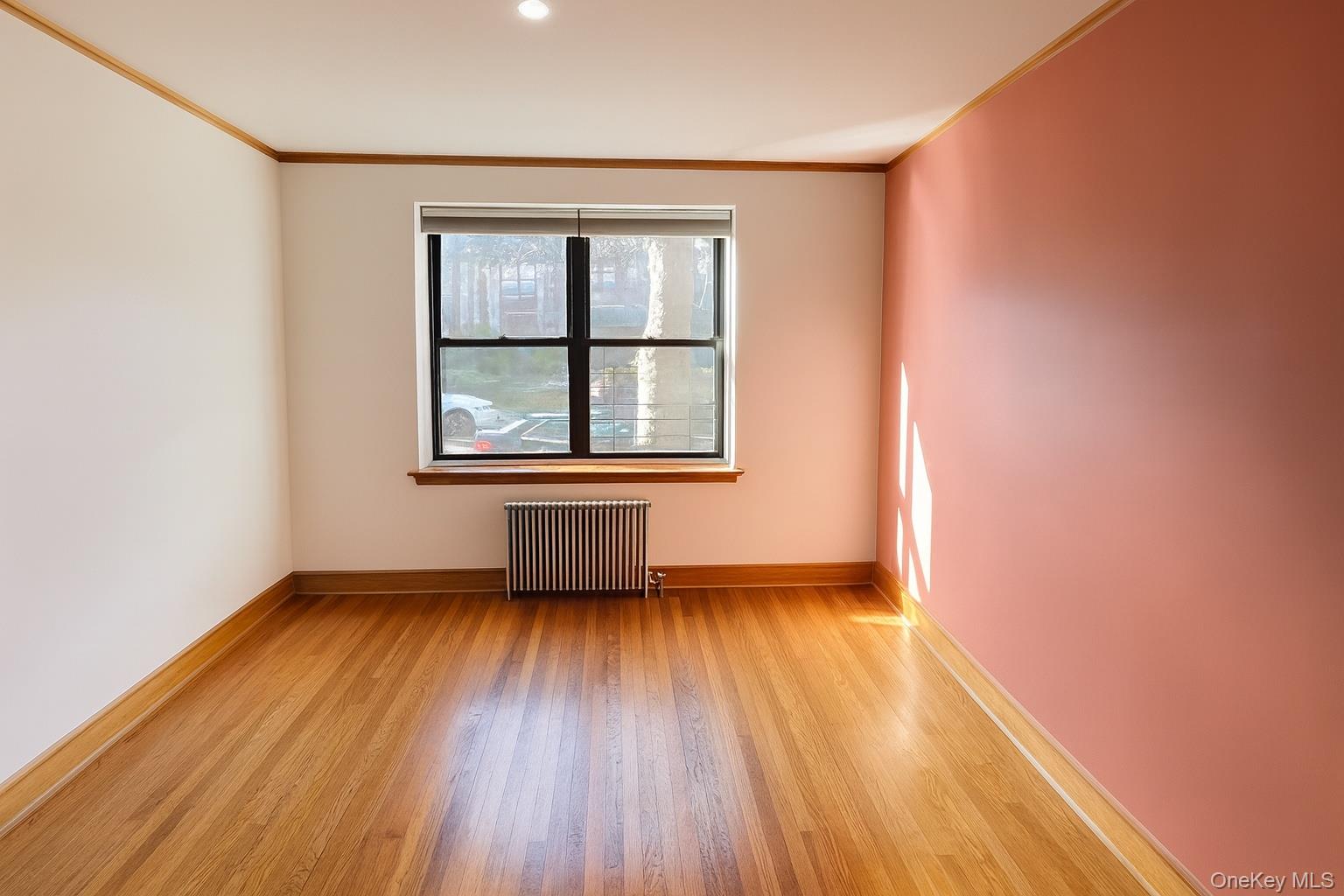 21-41 78th Street, Unit 1 Queens, NY 11370 - Photo 8 of 10 an empty room with wooden floor and windows