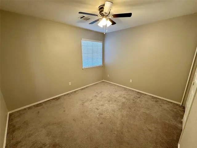 an empty room with a window and ceiling fan