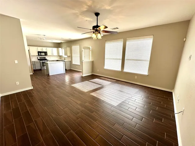 a view of a room with wooden floor a ceiling fan and windows