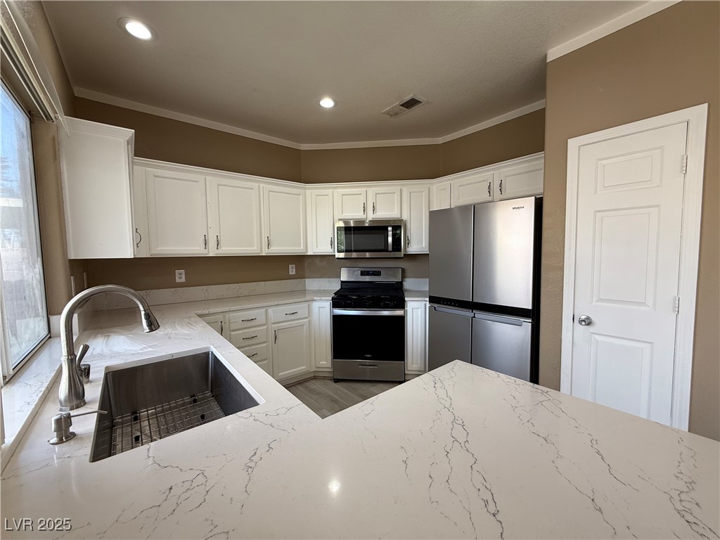 7062 Russell Ranch Avenue Las Vegas, NV 89113 - Photo 18 of 32 Kitchen with visible vents, light stone countertops, a sink, and stainless steel appliances