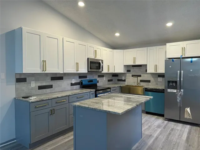 a kitchen with stainless steel appliances granite countertop a refrigerator stove microwave and sink