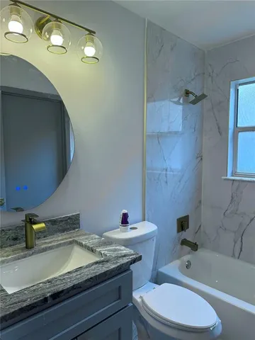a bathroom with a granite countertop sink a toilet and bathtub