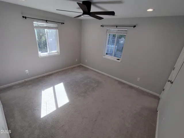 en empty room with windows and ceiling fan