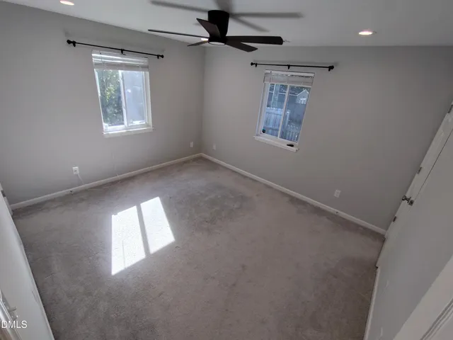 en empty room with windows and ceiling fan