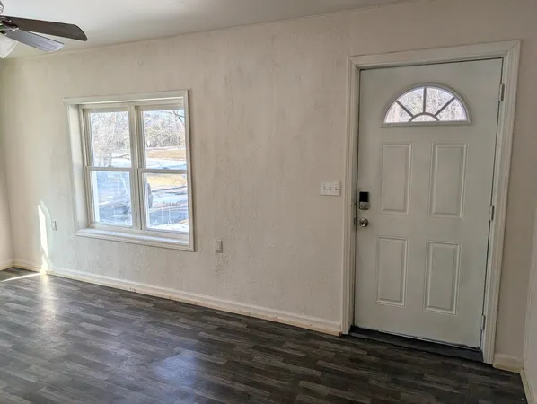 a view of empty room with wooden floor and window