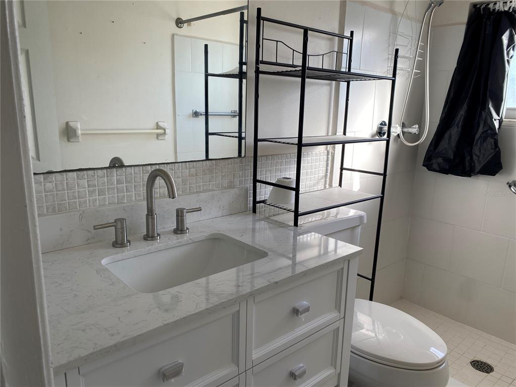 911 Washington Avenue Southwest, Unit 212 Largo, FL 33770 - Photo 12 of 20 a bathroom with a granite countertop sink a toilet a vanity and mirror