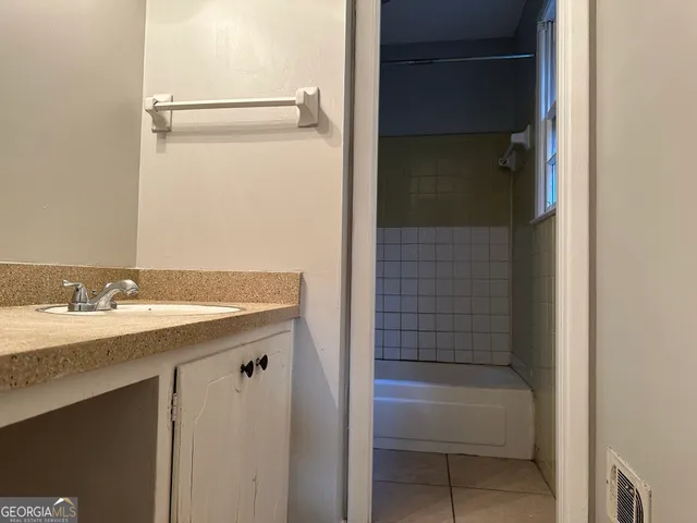 a bathroom with a granite countertop sink and a bathtub