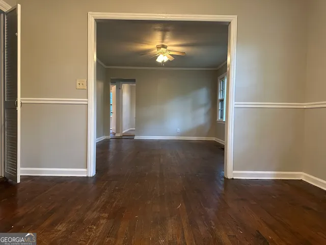 an empty room with wooden floor chandelier and windows