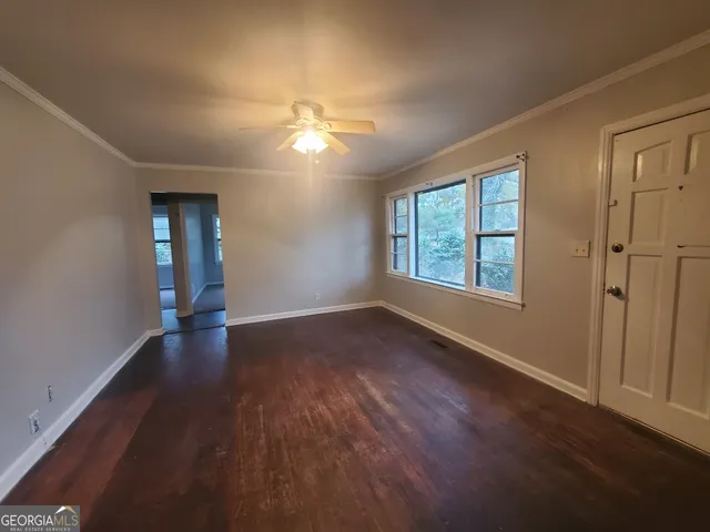 an empty room with wooden floor chandelier fan and windows