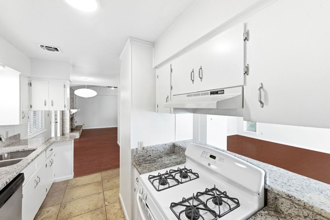 6210 Shadow Valley Drive, Unit A Austin, TX 78731 - Photo 13 of 29 Kitchen with white gas range, light stone countertops, white cabinetry, and stainless steel dishwasher