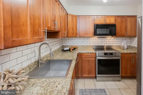 a kitchen with stainless steel appliances granite countertop a stove a sink and a microwave