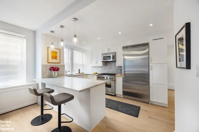 a kitchen with stainless steel appliances kitchen island granite countertop a sink and a refrigerator