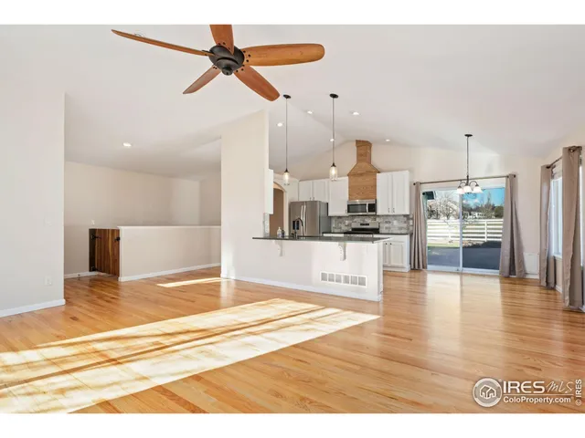 a view of a kitchen with kitchen island stainless steel appliances wooden floor and a view of living room