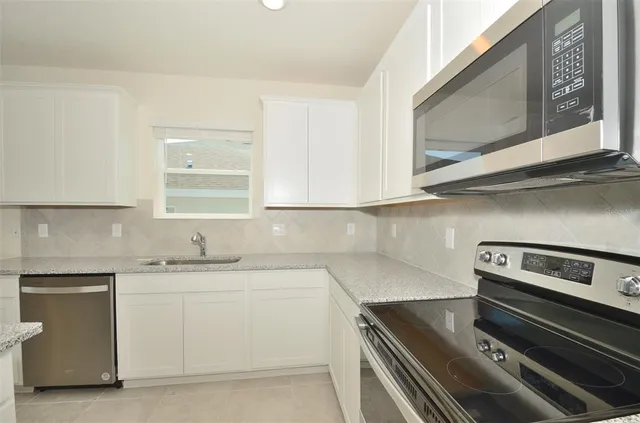 a kitchen with stainless steel appliances a refrigerator a sink a stove top oven a counter space and cabinets