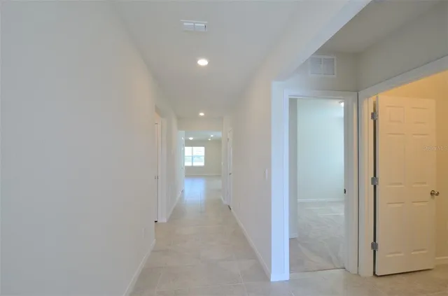 a view of a hallway with wooden floor and a bathroom
