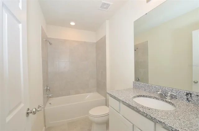 a bathroom with a granite countertop toilet a sink and a bathtub