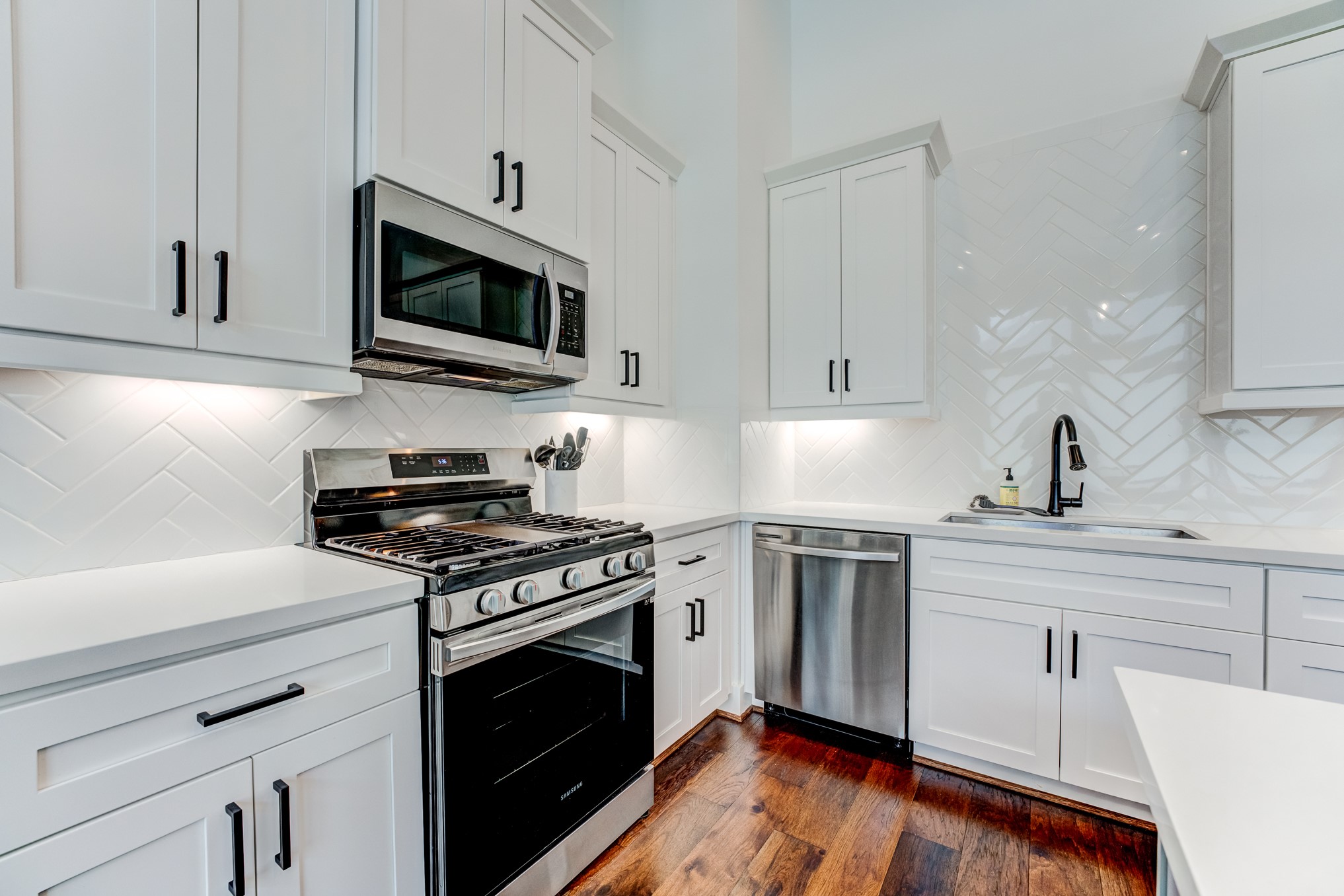 107 West Whitney Street, Unit E Houston, TX 77018 - Photo 23 of 48 a kitchen with stainless steel appliances granite countertop a sink dishwasher a stove and a microwave oven with wooden floor