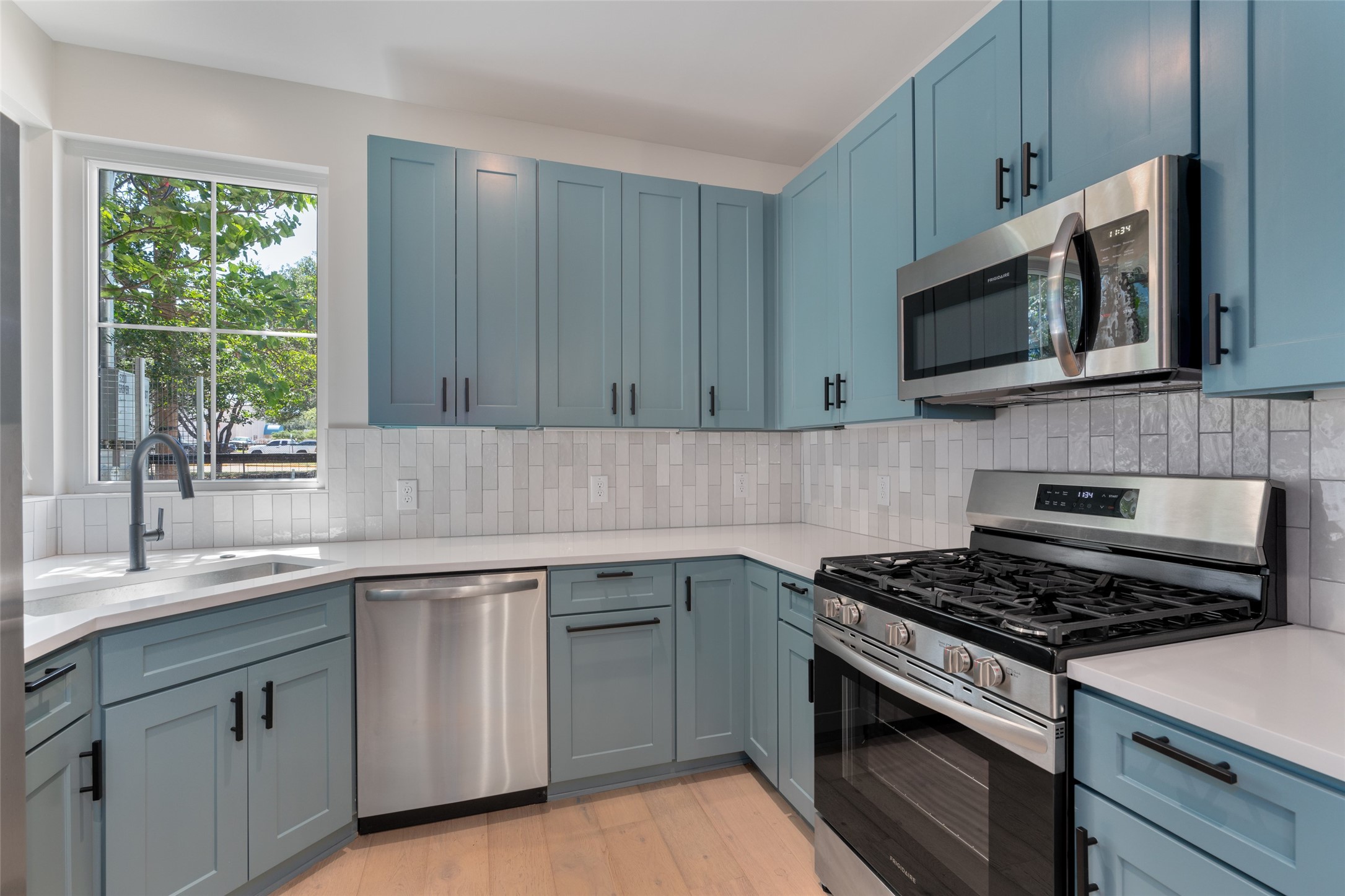 5200 Grover Avenue Austin, TX 78756 - Photo 8 of 32 Kitchen featuring light blue cabinetry, stainless steel appliances, white quartz countertops, and a subway tile backsplash