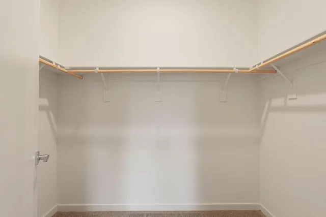 a view of a hallway with wooden floor and a bathroom