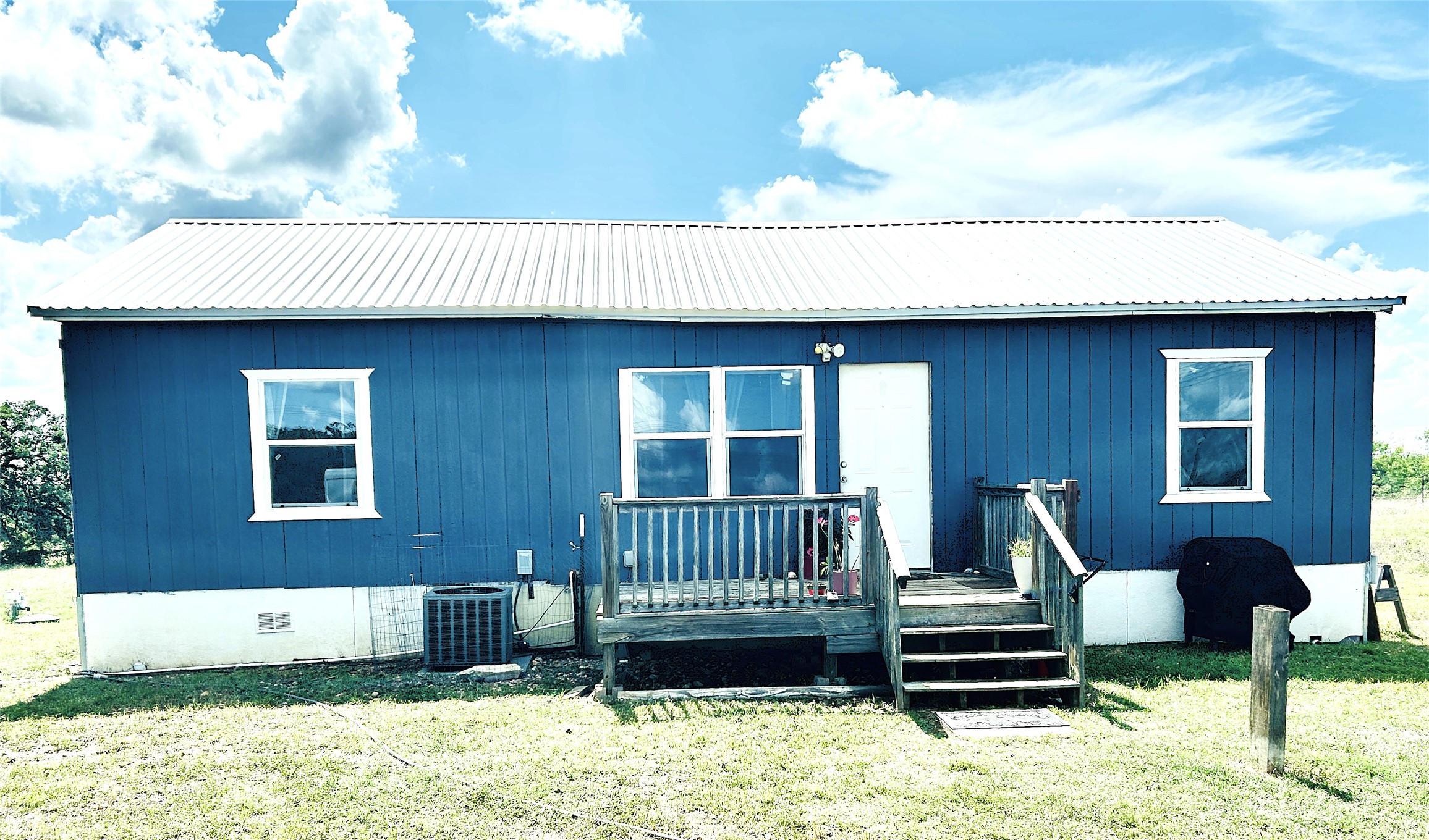 A vibrant blue siding and bright white trim complement this home's welcoming outdoor deck.